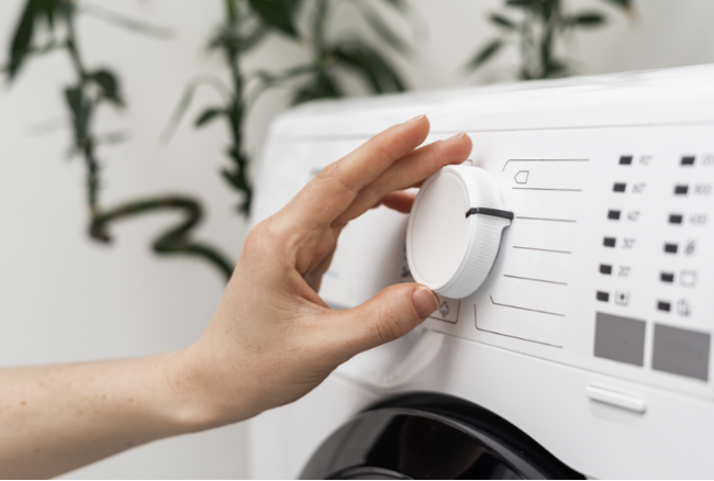 Person’s hand adjusts settings on a washing machine
