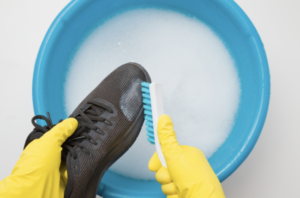 Person wearing yellow gloves scrubs black shoes over a solution