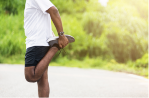 Man stretches outside in white shirt and black shorts
